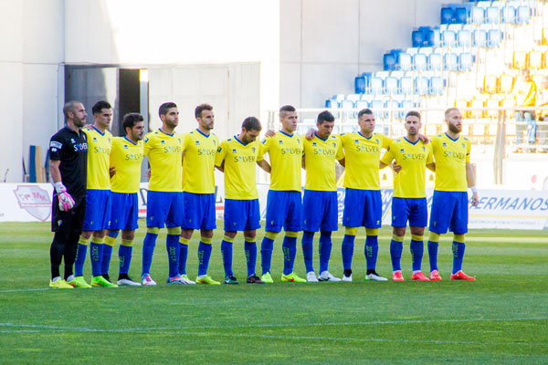 Abrazo entre jugadores durante un minuto de silencio en el estadio Ramón de Carranza / Trekant Media